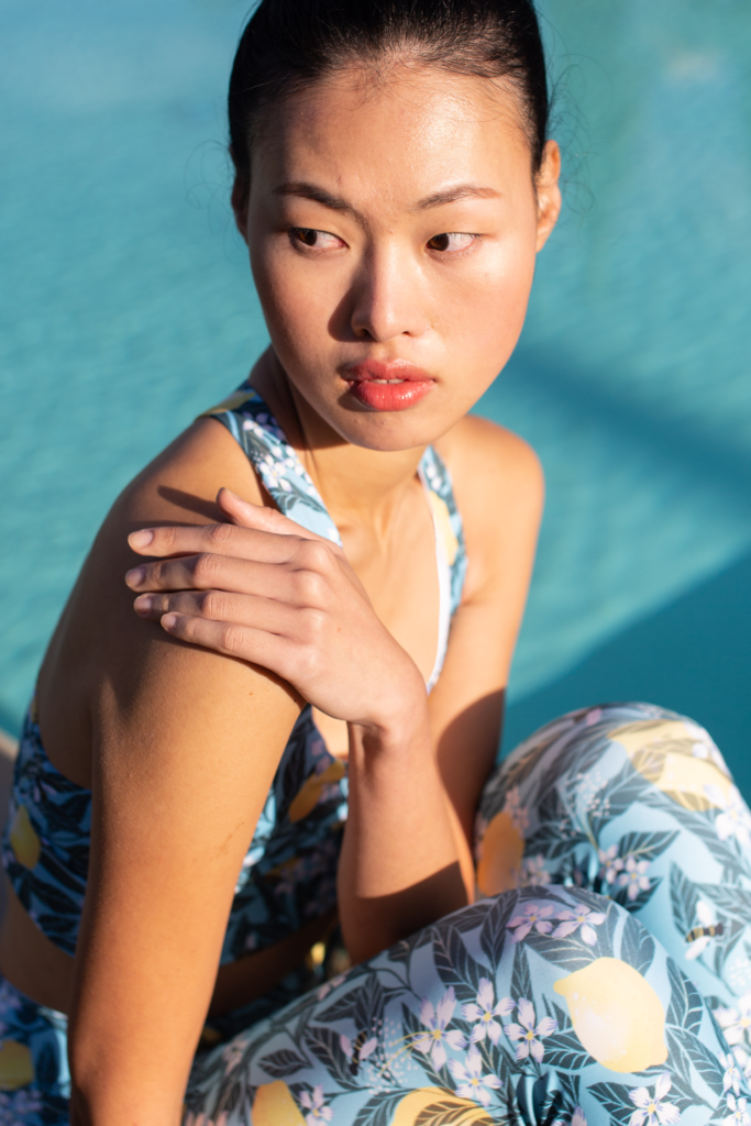 high end outdoor fashion editorial close up of model in printed lemon activewear set by a pool