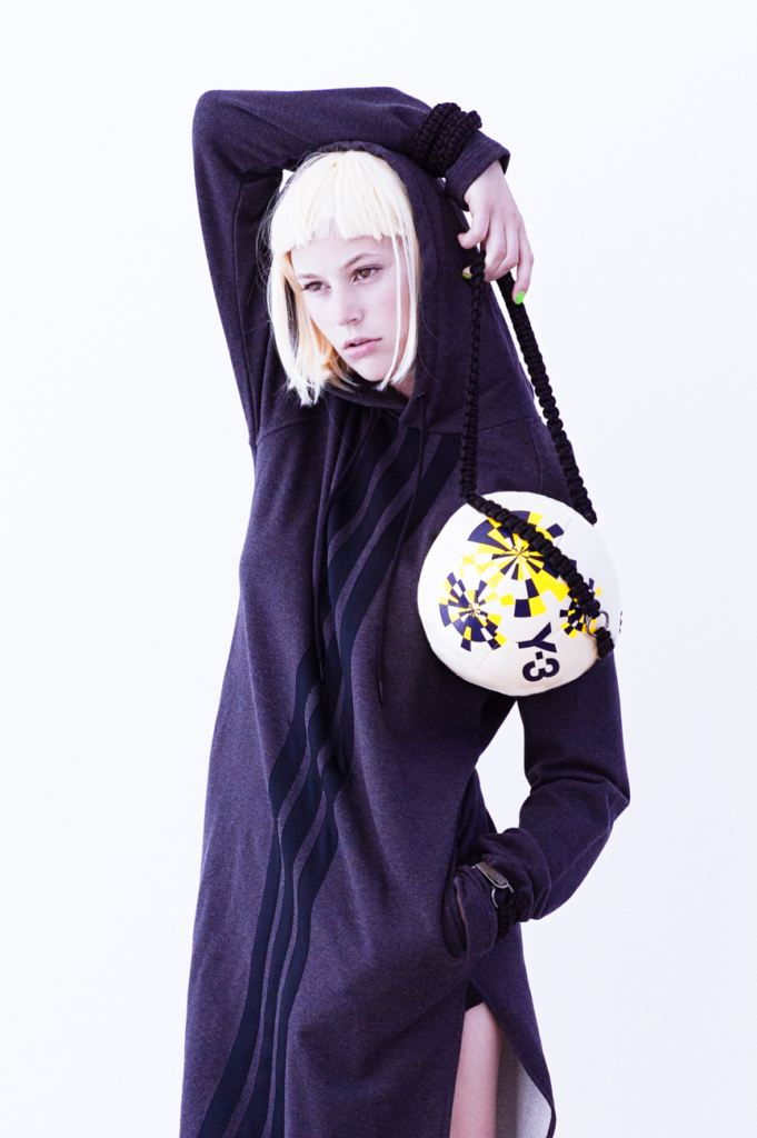 high fashion streetwear editorial portrait of model wearing dark oversized garment with graphic detail, arm raised
