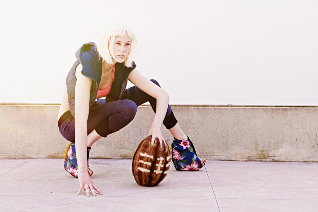 streetwear editorial of model crouching outdoors wearing fashion sportswear and holding textured ball