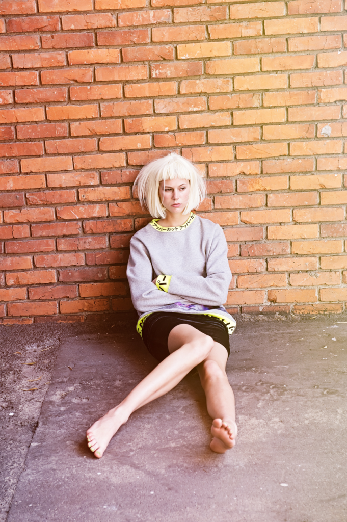 moody high end streetwear fashion editorial, model close up, brick wall, feet